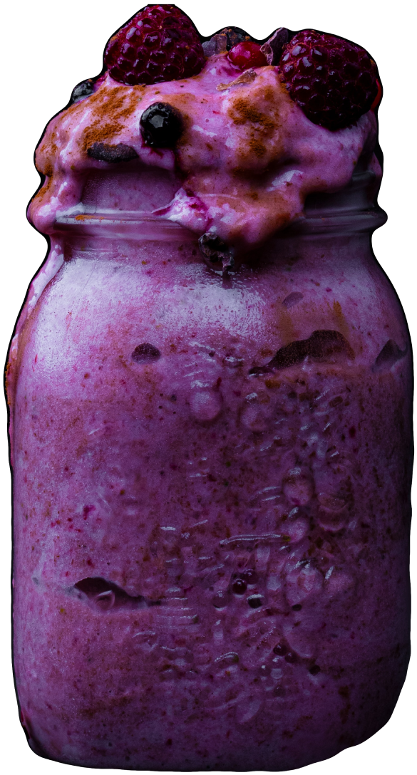 Thick purple smoothie, overflowing mason jar, topped with fresh blueberries and raspberries
